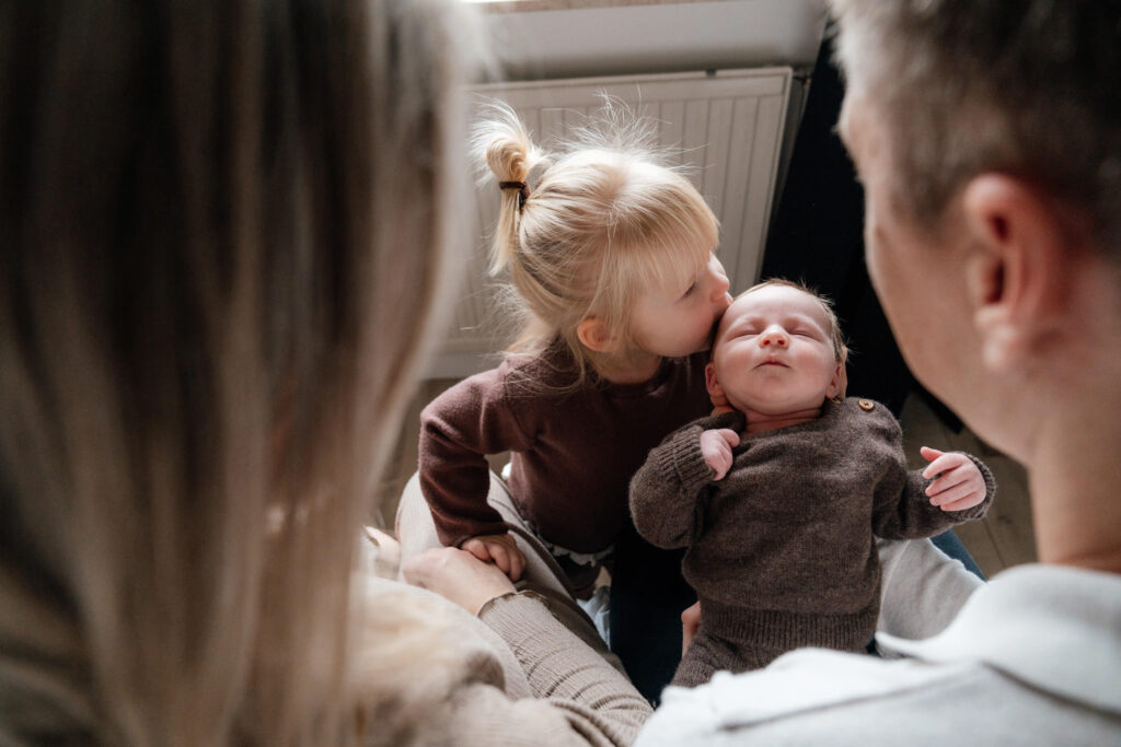 Gezin tijdens babyshoot zusje kust babybroertje in Rotterdam